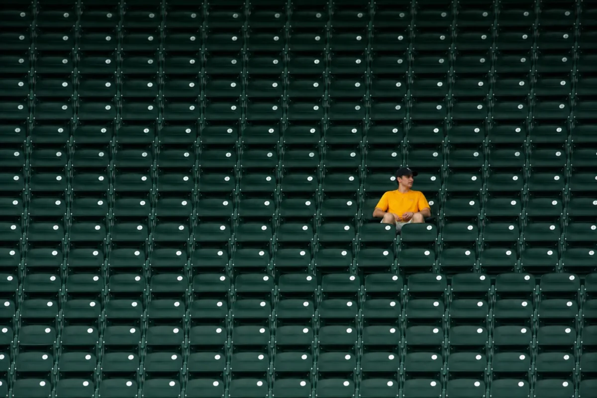 focal point pattern break Person in a yellow shirt creating a focal point by breaking a repeated stadium seat pattern