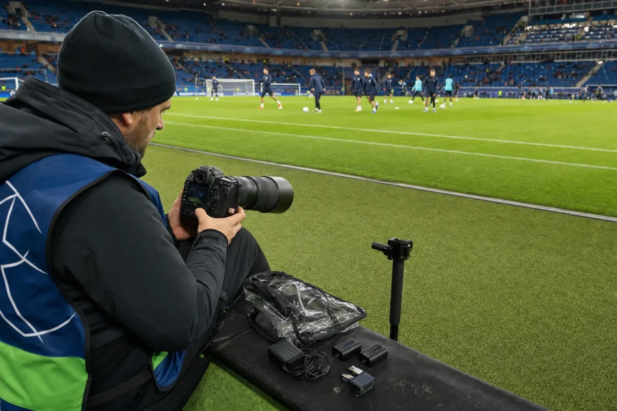 Photographer checking camera settings and gear before a soccer match