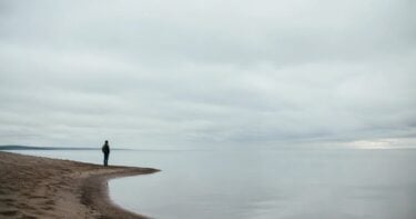 Negative Space in Photography: How to Make Simple Frames Stronger Small figure standing in a wide open landscape with calm negative space