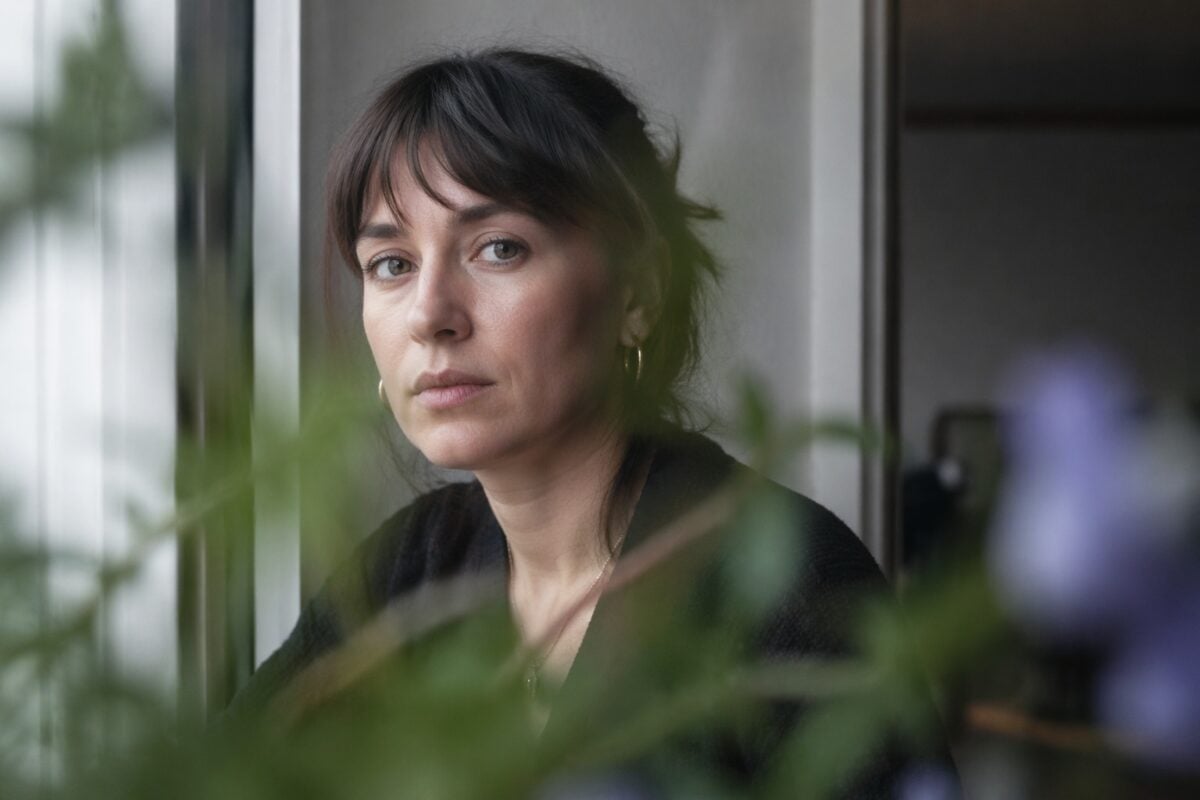 Portrait photographed through soft blurred foreground leaves while the face stays clear