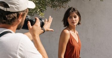 How to Take Better Portraits in Harsh Sunlight: Practical Tips for Real Outdoor Sessions Photographer directing a portrait subject in harsh outdoor sunlight while protecting natural skin tone