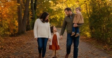 Family walking a tree-lined path in warm autumn light during a relaxed fall photo session