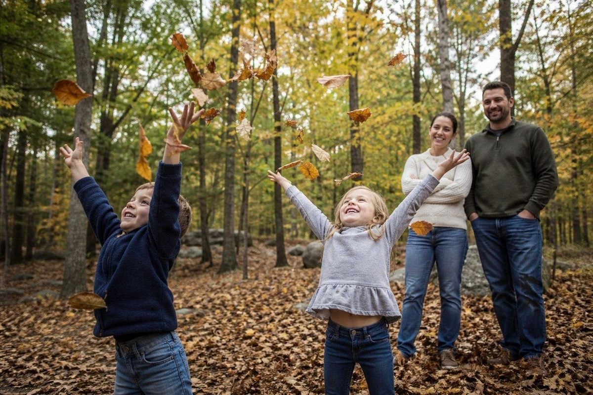 Kids tossing a small handful of autumn leaves while parents watch, faces still fully visible