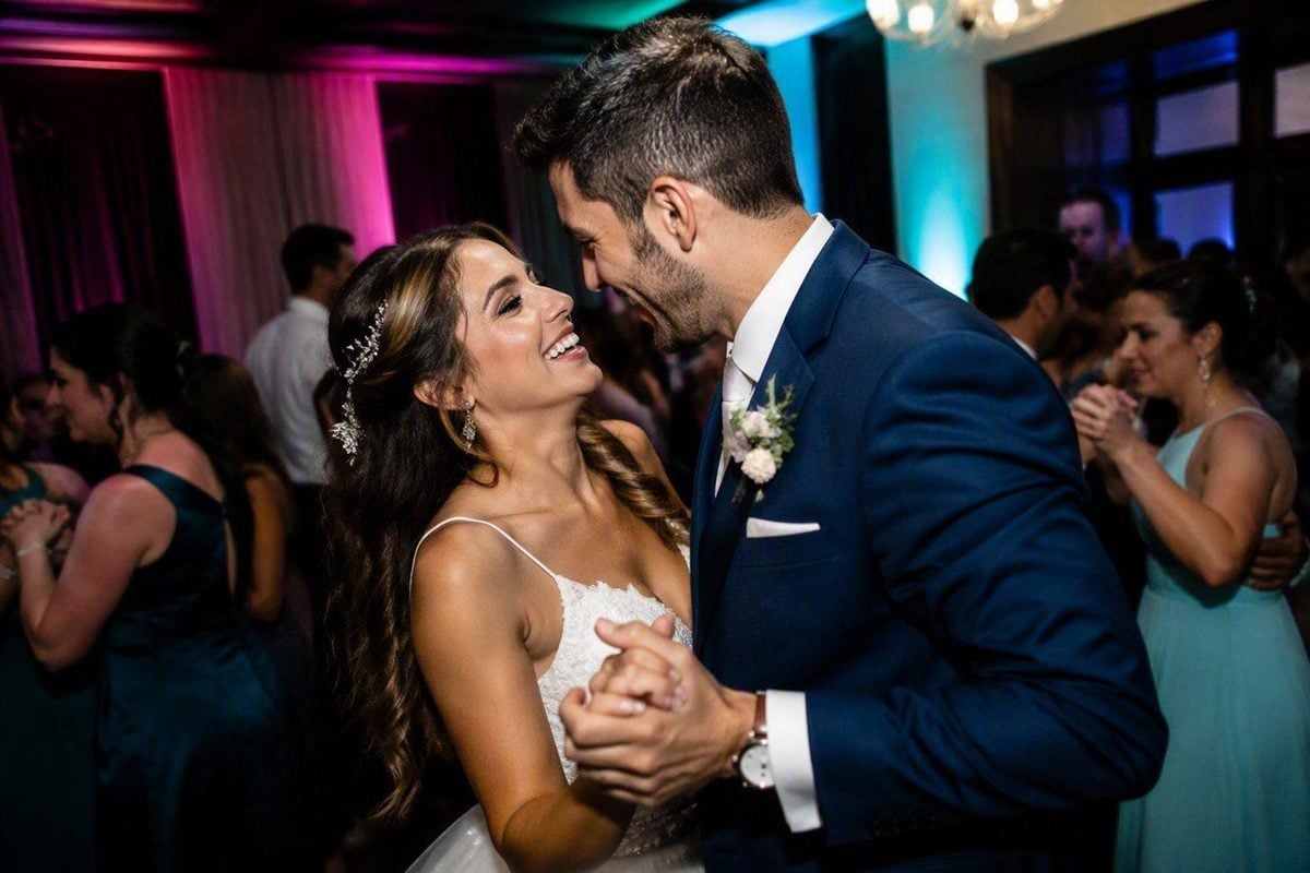 Dance floor reception photo with flash-lit couple and colorful ambient uplights in the background